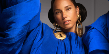 An image of singer Alicia Keys wearing a blue top with gold earrings