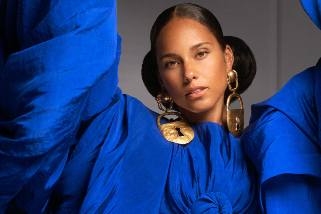 An image of singer Alicia Keys wearing a blue top with gold earrings