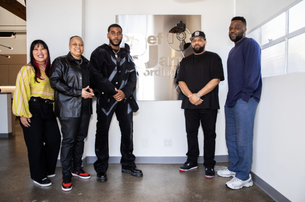 R&B singer pictured with Helen Yu, Natosha Cox, Jeremy “J Dot” Jones, and Tunji Balogun at his Def Jam signing