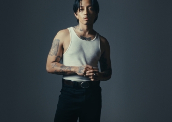 An image of R&B singer RINI posing confidently against a black backdrop.