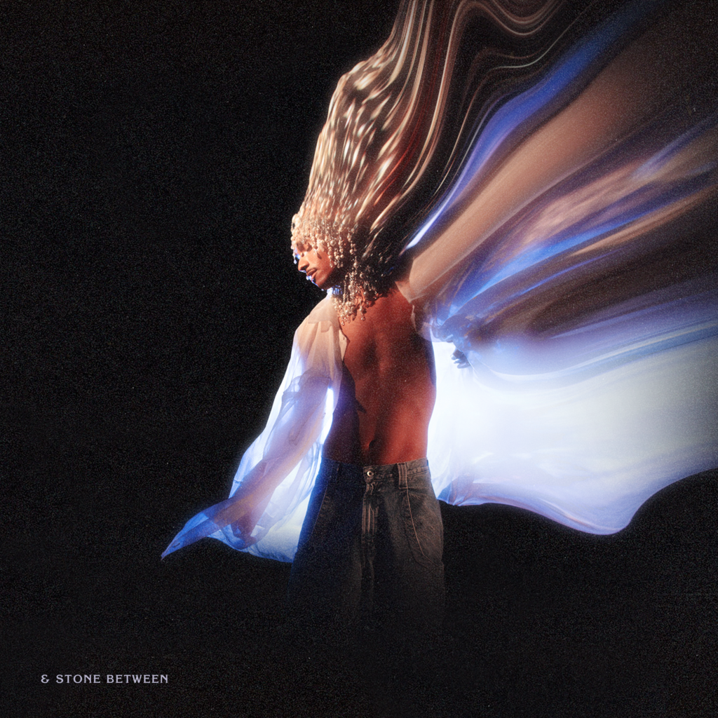 Forest Claudette's & Stone Between EP cover art with a dynamic swirl of multicolored light trails emanating from their head and shoulders, set against a dark background. They are turned away from the camera, showing their bare back and wearing jeans.
