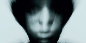 Gallant's Zinc album cover features a blurred portrait of him with an indistinct face, wearing a necklace, set against a dark, monochromatic background, creating a mysterious and eerie atmosphere.