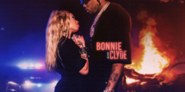 Promotional cover image for the song "Bonnie & Clyde" by artists Honey Bxby and Fivio Foreign. The image features both artists standing close together with a fiery explosion and overturned cars in the background. Both artists are dressed in stylish, urban outfits. Honey Bxby is holding a microphone while Fivio Foreign has several chains around his neck. The title "Bonnie & Clyde" is prominently displayed at the top in bold, stylized text.