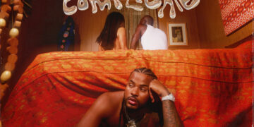 This is an album cover for "It's Complicated" by Trevor Jackson. The image depicts Trevor Jackson lying on a red bed, gazing directly at the camera with an intense expression. In the background, a couple is visible under a sheer red fabric, which adds a layer of complexity to the scene. Above the bed hang wooden beads, casting patterns on Jackson and the drapery. The cover contains explicit content warning and artist's name in bold letters.