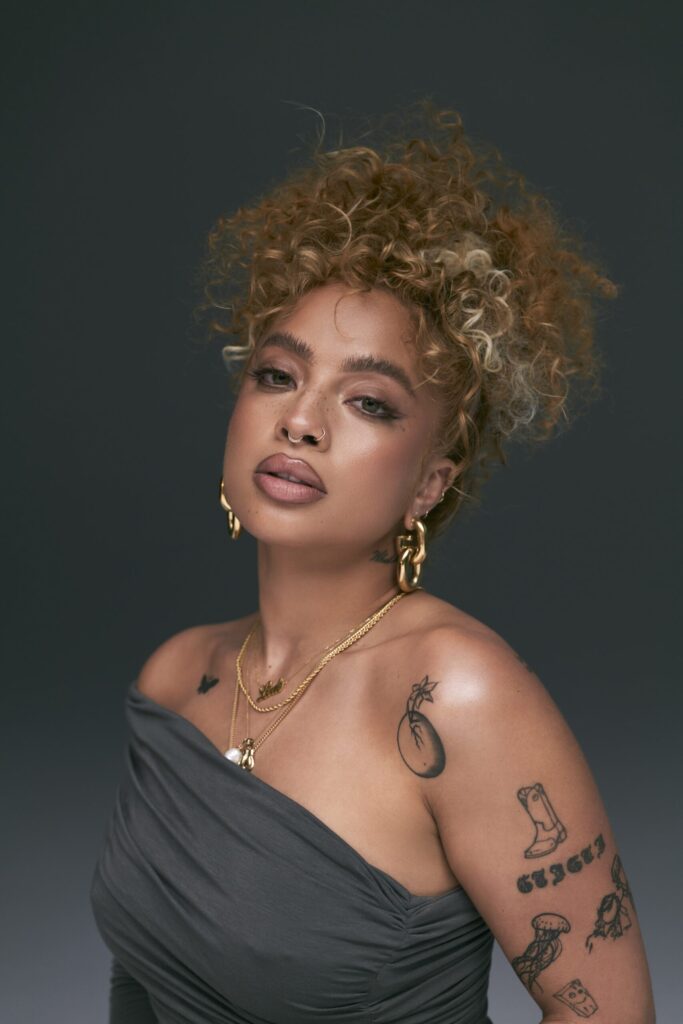A photo of R&B singer Kiana Ledé against a green backdrop