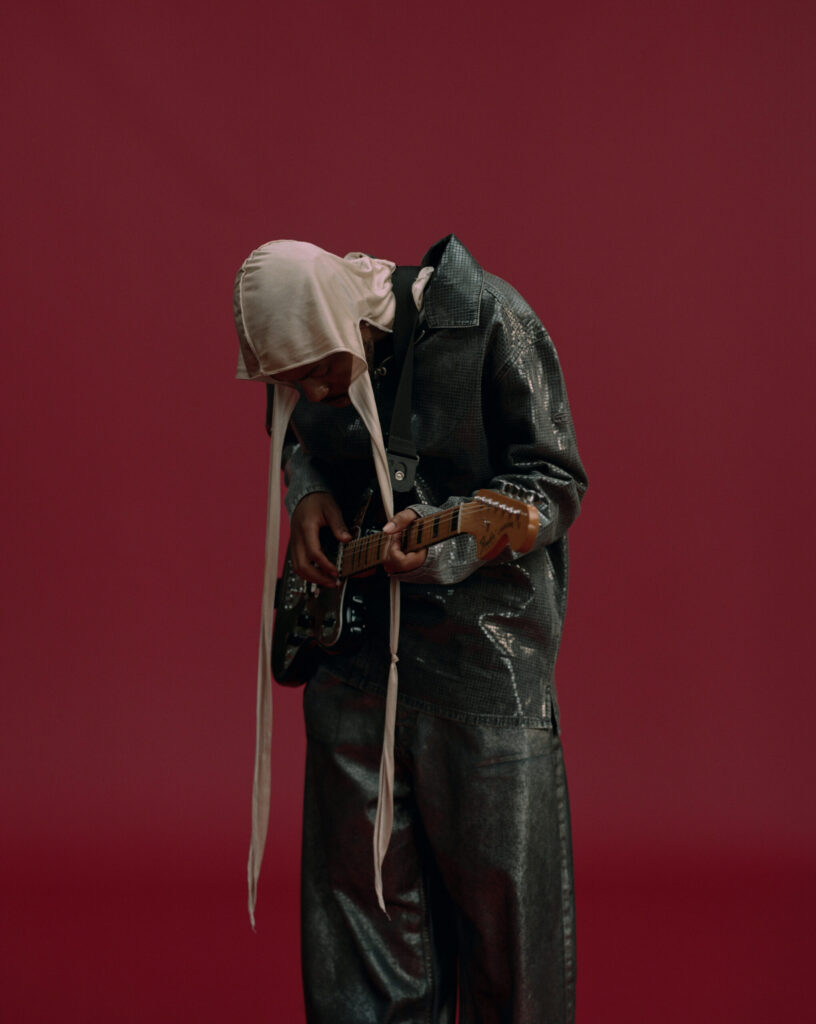 A photo of singer-songwriter Montell Fish against a maroon backdrop