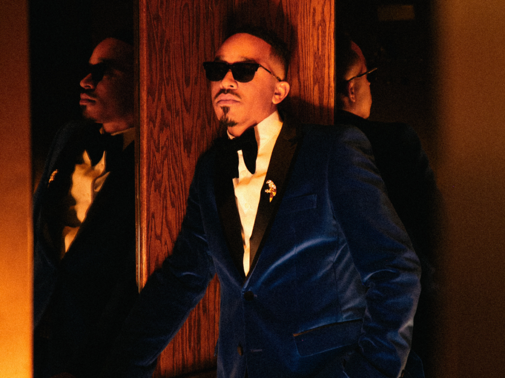 A photo of R&B singer October London in a blue suede suit and wearing dark shades