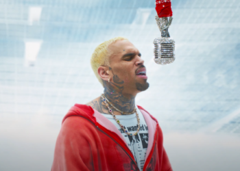 Chris Brown in his "Residuals" video: He is wearing a red jacket singing into a diamond-studded microphone