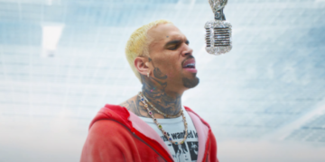 Chris Brown in his "Residuals" video: He is wearing a red jacket singing into a diamond-studded microphone
