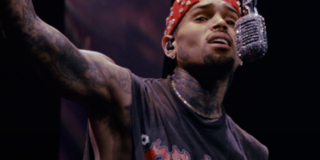 Chris Brown in his "Residuals" video: He is wearing a read jacket singing into a diamond-studded microphone