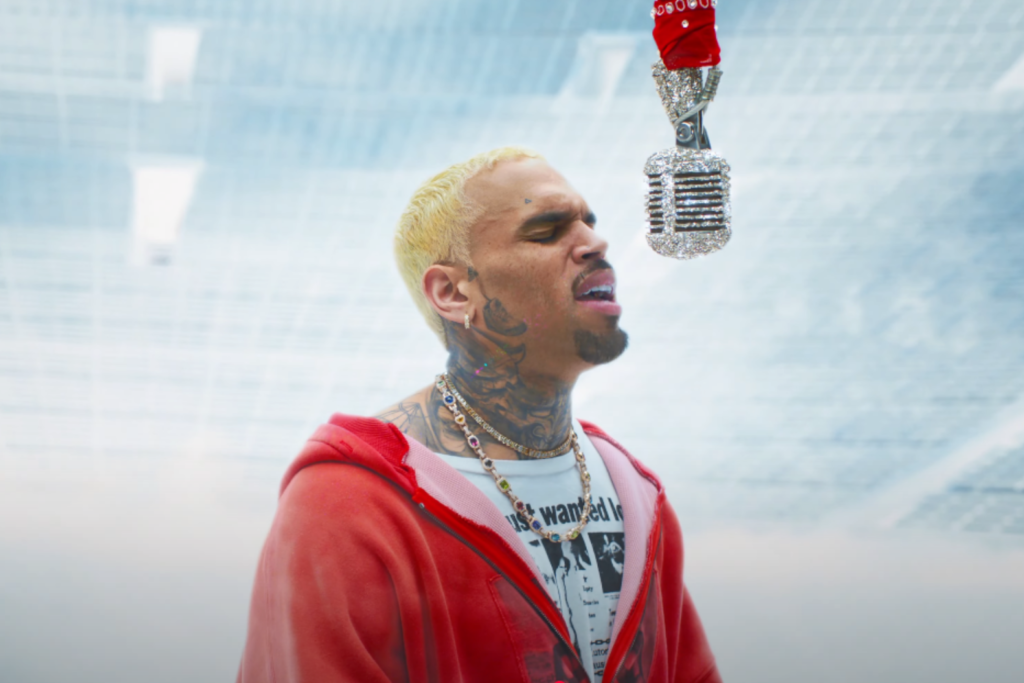 Chris Brown in his "Residuals" video: He is wearing a red jacket singing into a diamond-studded microphone