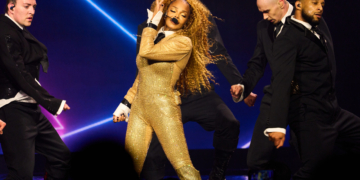 Janet Jackson dazzles in a gold bodysuit, performing on stage with fellow dancers at Resorts World Theatre.