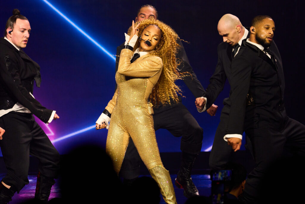 Janet Jackson dazzles in a gold bodysuit, performing on stage with fellow dancers at Resorts World Theatre.