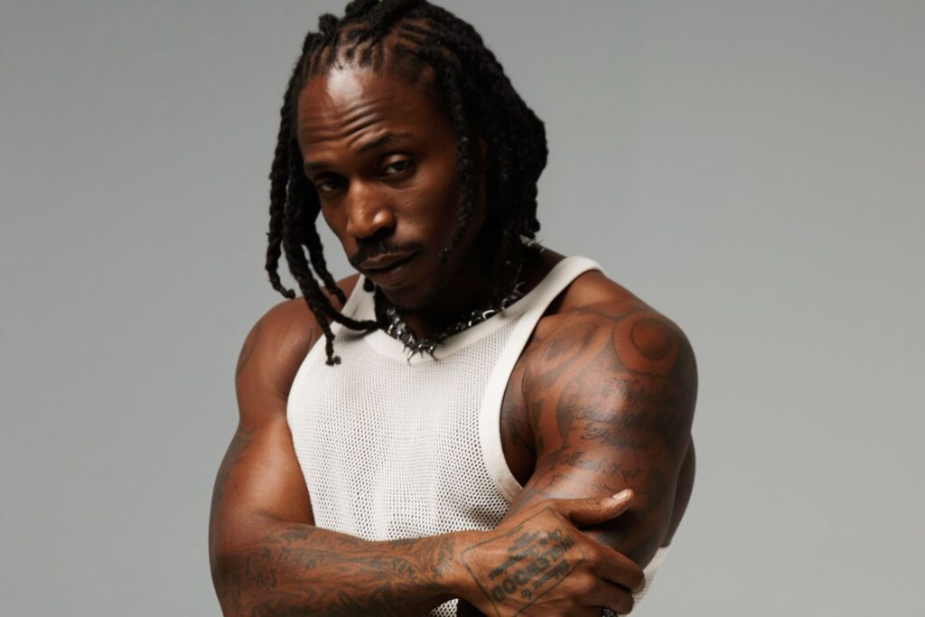 R&B singer SiR poses against a grey backdrop in a white tank top.