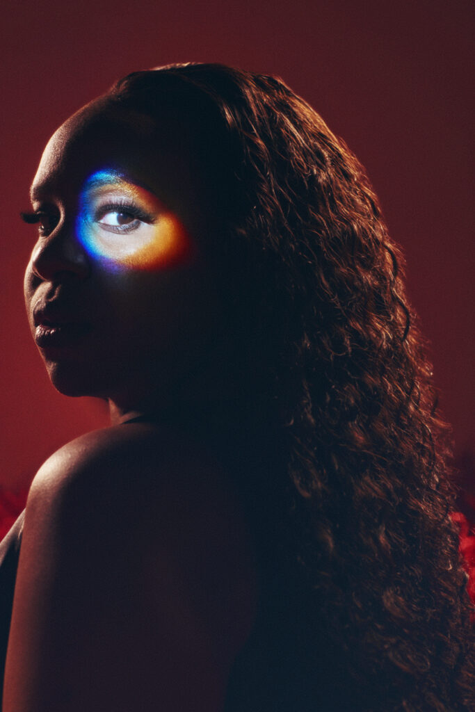 A photo of Nao standing in front of a red backdrop.