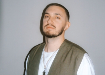 A photo of singer Joe Leone standing in front of a gray wall