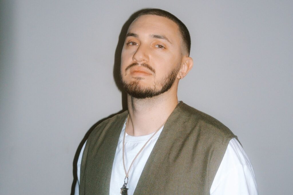 A photo of singer Joe Leone standing in front of a gray wall