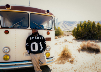 A photo of Xavier Omar standing in front of a bus in a mountainous area