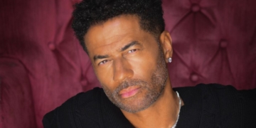 A photo of Eric Benét sitting on a burgundy velvet chair