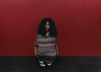 A photo of SZA wearing Vans against a red wall