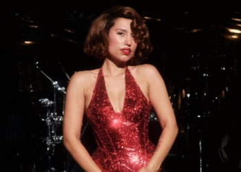 A photo of singer RAYE in a shimmering red dress