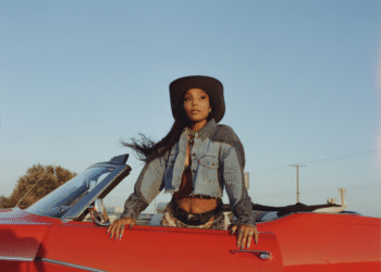 India Shawn in a red car wearing a denim western jacket and hat