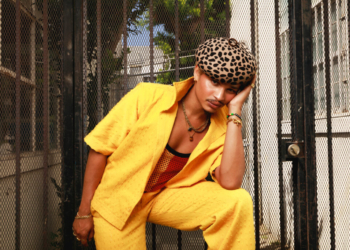 A photo of Destin Conrad wearing matching yellow shirt and pants with a cheetah print hat
